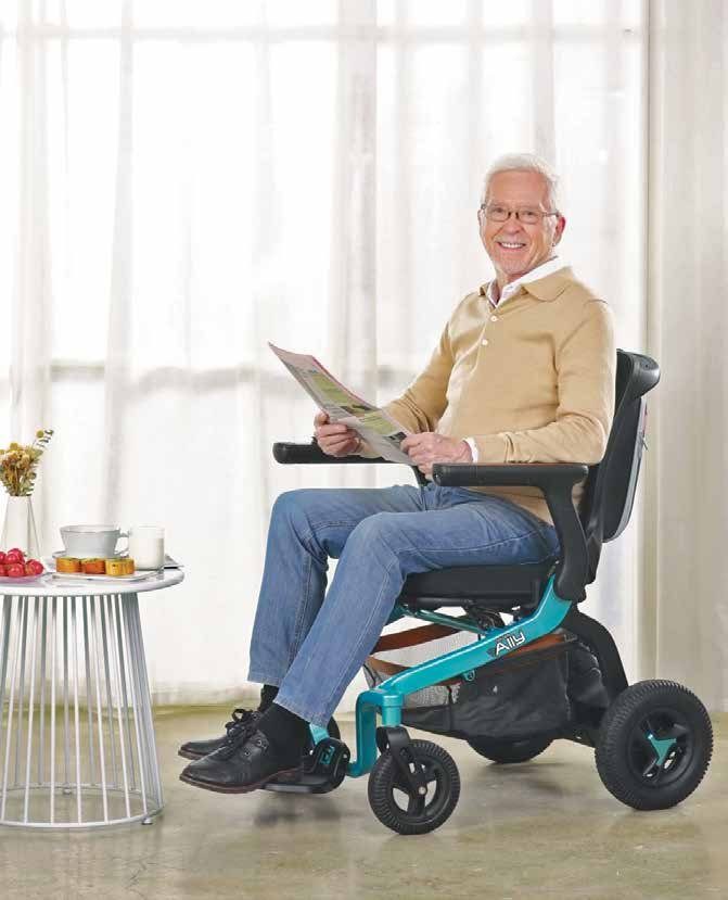 A smiling man seated in a lightweight power wheelchair at home